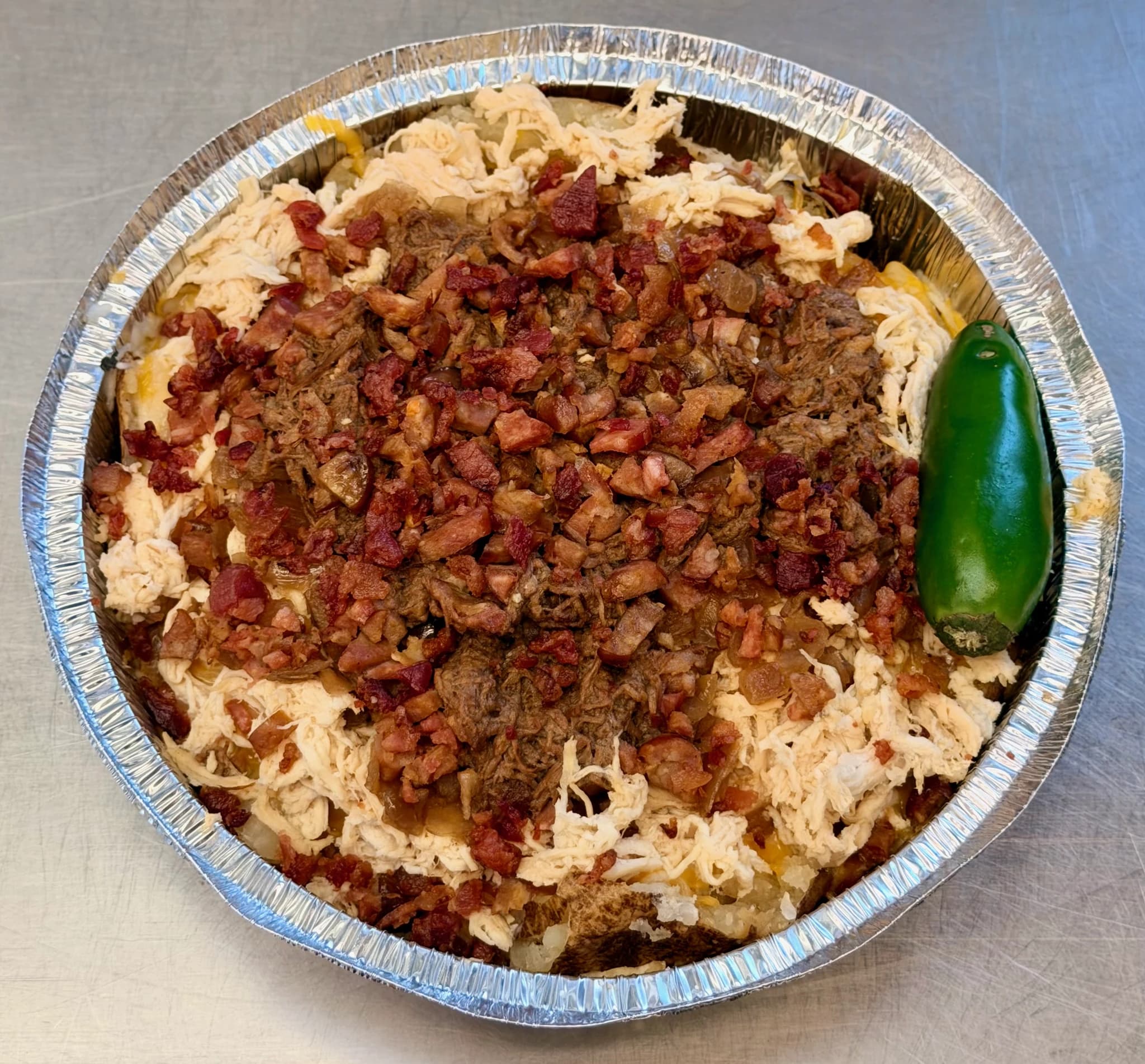 A CHUBBYS potato topped with meat, bacon, and a jalapeño